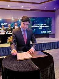 Juan Pablo Carrasco firmando papeles en una conferencia