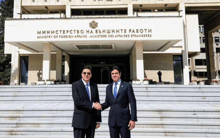 Dos funcionarios con traje oscuro estrechando la mano en un encuentro diplomático oficial frente a la entrada del edificio del Ministerio de Asuntos Exteriores.